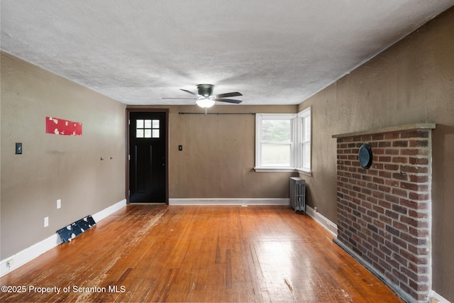 730 Chase Rd, Shavertown, PA 18708 - unfurnished living room featuring radiator, hardwood / wood-style floors, ceiling fan, healthy amount of natural light, and a textured ceiling