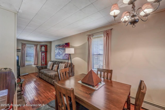 dining space featuring a baseboard heating unit, an inviting chandelier, and hardwood / wood-style flooring