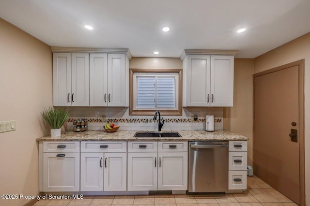 kitchen with stainless steel dishwasher, a sink, backsplash, and light stone counters