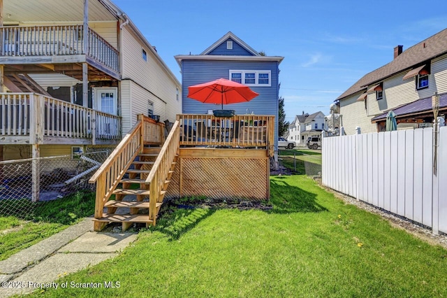 view of playground with fence, a yard, stairway, and a deck