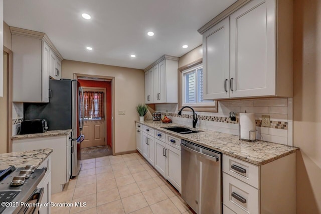 kitchen featuring backsplash, stainless steel appliances, light stone counters, and a sink