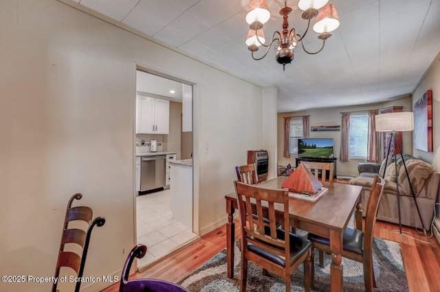 dining room featuring an inviting chandelier, heating unit, and light wood-style flooring