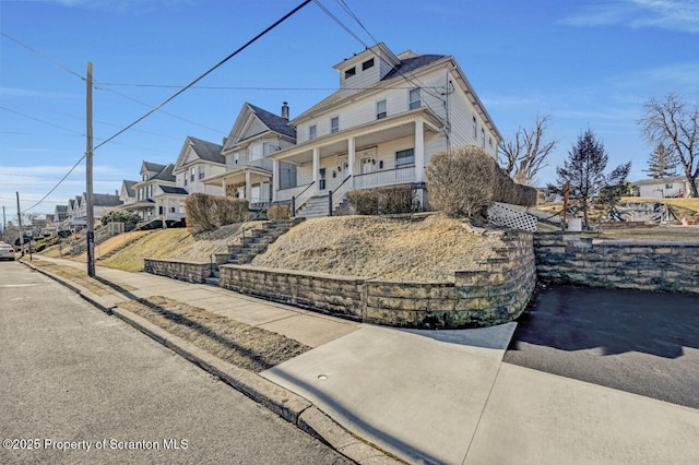 american foursquare style home with a residential view, a porch, and stairway