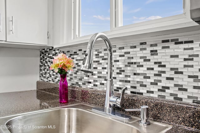 room details featuring tasteful backsplash, white cabinets, and a sink