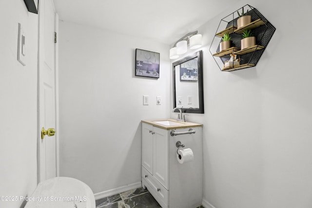 half bath with toilet, marble finish floor, vanity, and baseboards