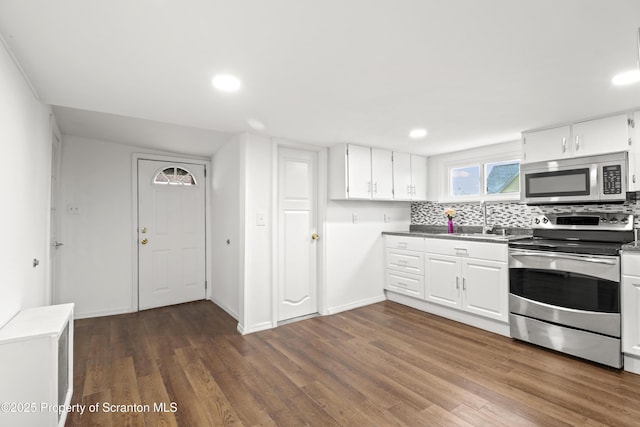 kitchen with appliances with stainless steel finishes, a sink, dark wood finished floors, and white cabinets