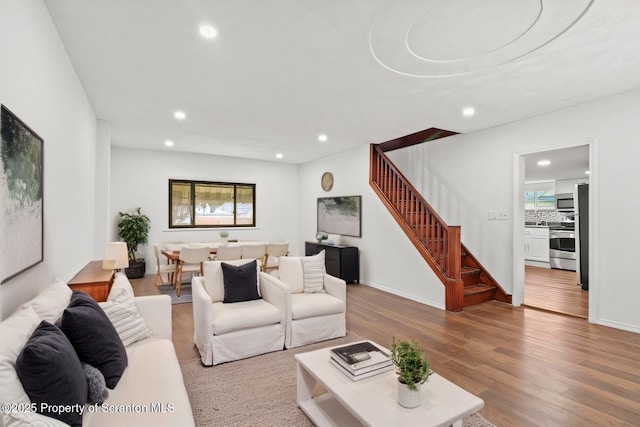 living area with a healthy amount of sunlight, stairway, wood finished floors, and recessed lighting