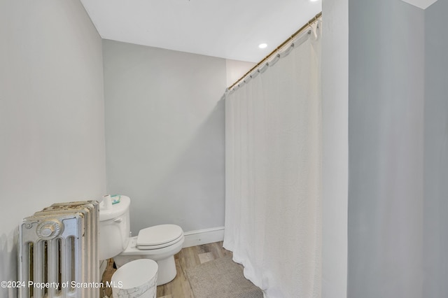 bathroom with hardwood / wood-style flooring, toilet, and radiator