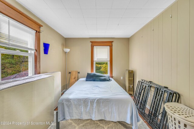 bedroom with radiator and wooden walls