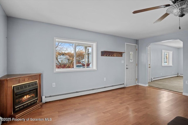 unfurnished living room with ceiling fan, light hardwood / wood-style floors, heating unit, and a baseboard heating unit