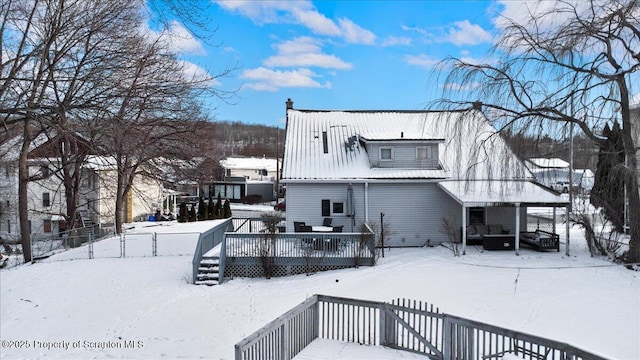 snow covered rear of property with a wooden deck