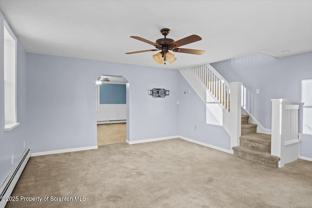 unfurnished living room featuring ceiling fan, a baseboard heating unit, and light carpet