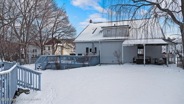 snow covered back of property featuring a wooden deck