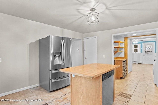 kitchen with butcher block countertops, appliances with stainless steel finishes, hanging light fixtures, a baseboard radiator, and light tile patterned flooring