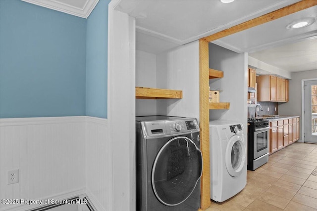 laundry room with washer and clothes dryer, crown molding, and light tile patterned floors