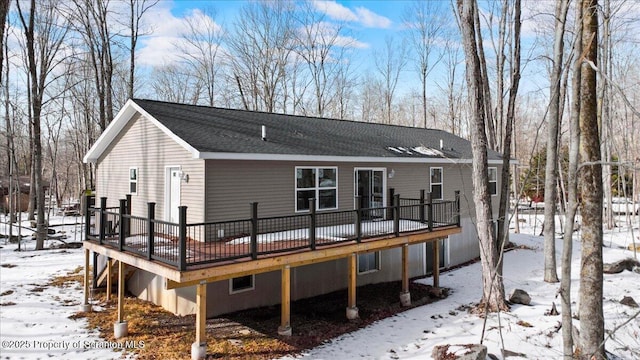 snow covered back of property with a wooden deck