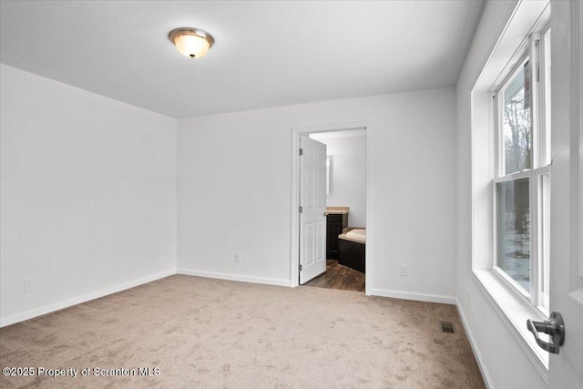 unfurnished bedroom featuring ensuite bath and dark colored carpet