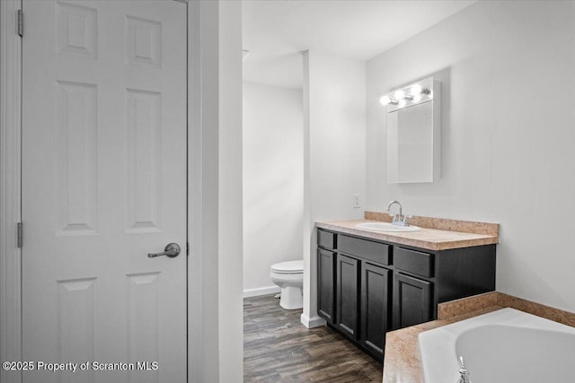 bathroom with vanity, toilet, hardwood / wood-style floors, and a tub