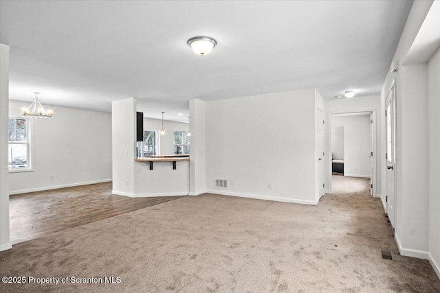 unfurnished living room featuring a chandelier and carpet flooring