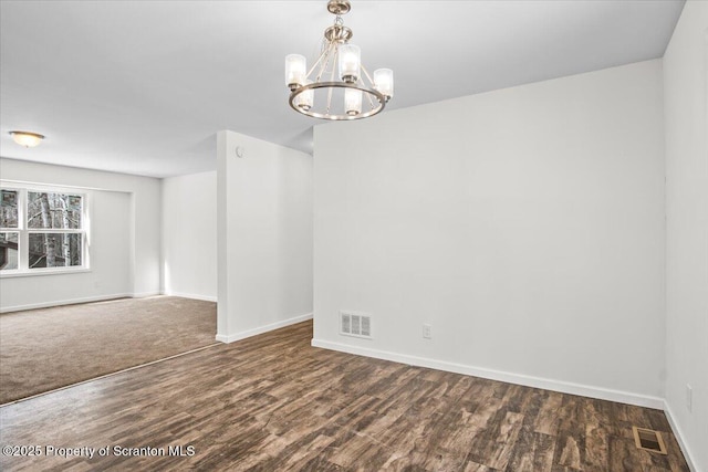 empty room featuring dark hardwood / wood-style floors and an inviting chandelier