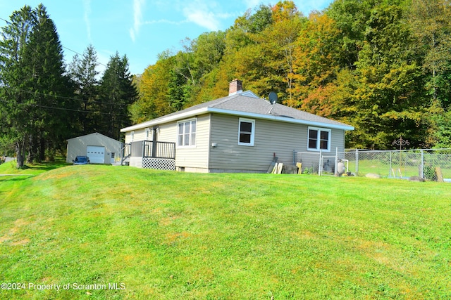 rear view of property featuring an outbuilding, a garage, and a lawn