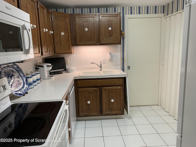 kitchen featuring sink, white appliances, and light tile patterned flooring