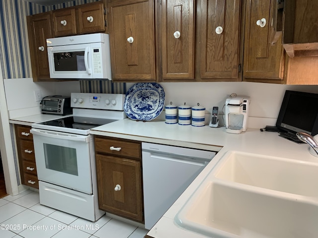 kitchen featuring white appliances, sink, and light tile patterned floors