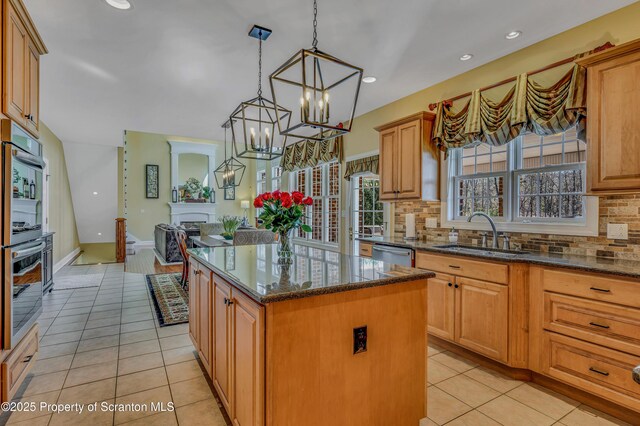 kitchen featuring a sink, light tile patterned floors, appliances with stainless steel finishes, and a fireplace