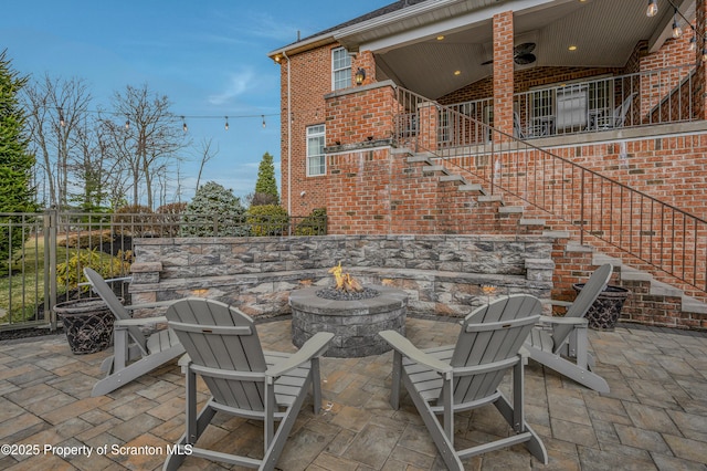 view of patio with fence, a fire pit, and stairway