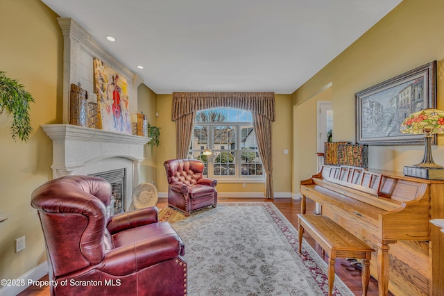 sitting room featuring baseboards, recessed lighting, wood finished floors, and a fireplace