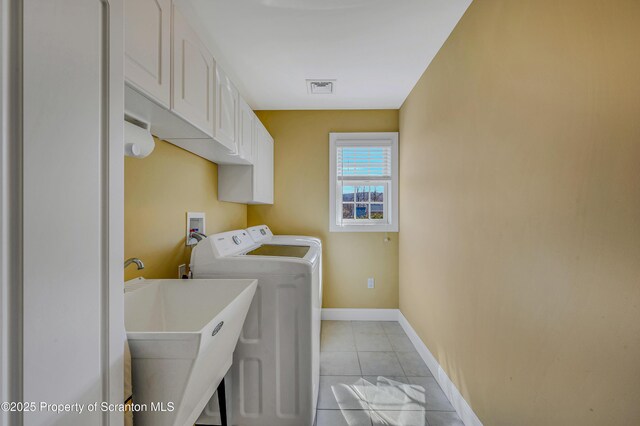washroom featuring light tile patterned floors, baseboards, visible vents, separate washer and dryer, and cabinet space