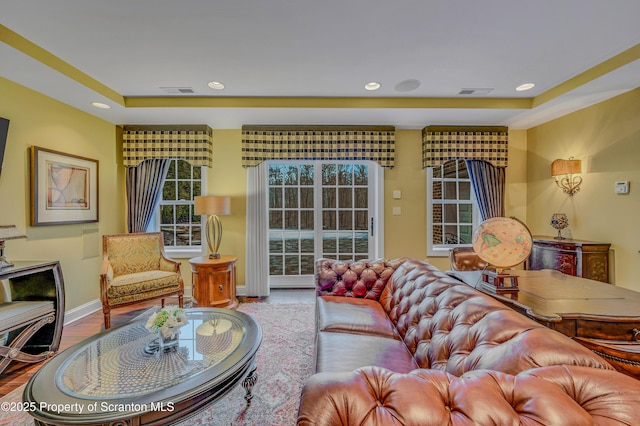 living area featuring a raised ceiling, visible vents, and recessed lighting