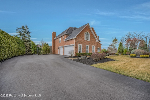 view of home's exterior with aphalt driveway, a yard, fence, brick siding, and an attached garage