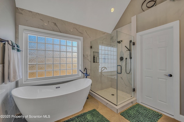 bathroom with a stall shower, tile patterned flooring, vaulted ceiling, and a freestanding bath