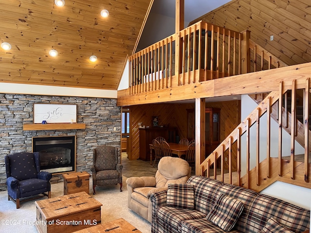 carpeted living room with a fireplace, high vaulted ceiling, wooden ceiling, and wood walls