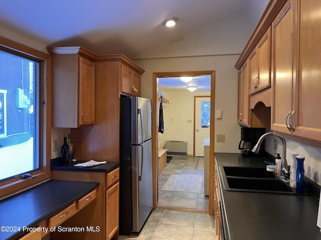 kitchen featuring stainless steel refrigerator, sink, light tile patterned floors, and vaulted ceiling