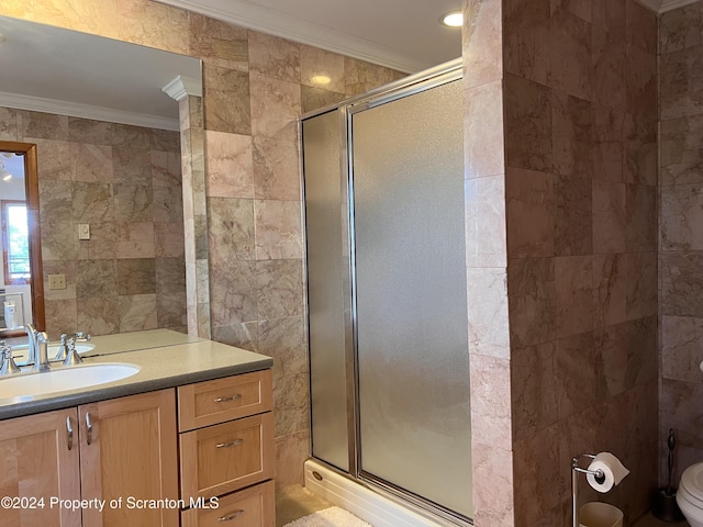 bathroom featuring crown molding, toilet, a shower with door, vanity, and tile walls