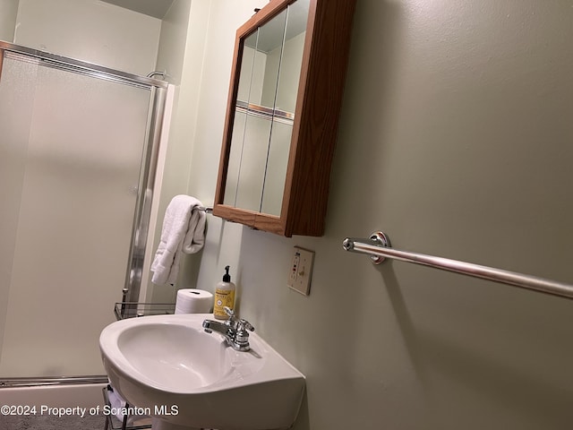 bathroom with sink and a shower with door