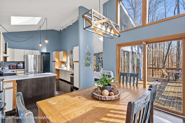 living area with a ceiling fan, a skylight, wood finished floors, and high vaulted ceiling