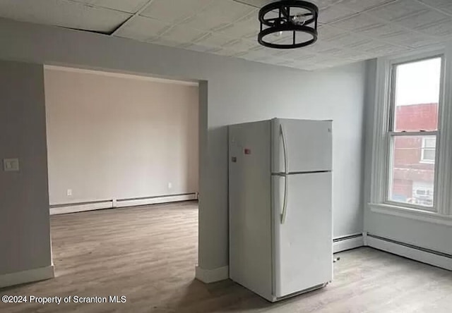 kitchen featuring baseboard heating, a healthy amount of sunlight, white fridge, and light wood-type flooring