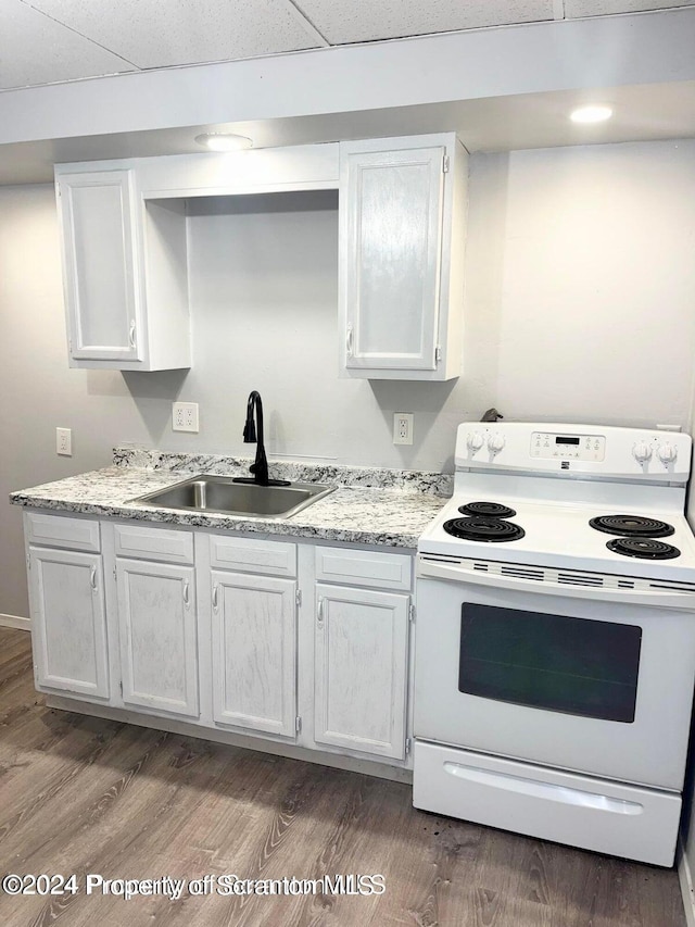 kitchen with white cabinetry, sink, hardwood / wood-style flooring, and white range with electric cooktop