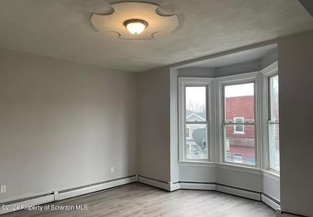 empty room featuring light hardwood / wood-style flooring and a baseboard radiator