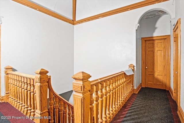 hallway with arched walkways, carpet flooring, and an upstairs landing