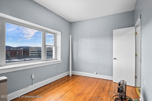 spare room with baseboards and wood finished floors