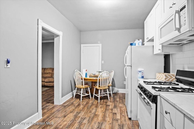 kitchen featuring white appliances, baseboards, decorative backsplash, white cabinets, and wood finished floors