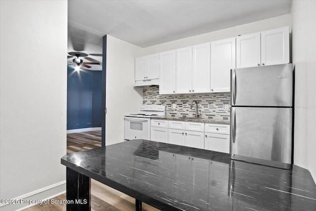 kitchen featuring white electric stove, decorative backsplash, freestanding refrigerator, a sink, and under cabinet range hood