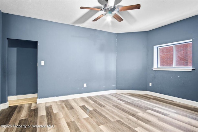 empty room featuring ceiling fan, wood finished floors, and baseboards