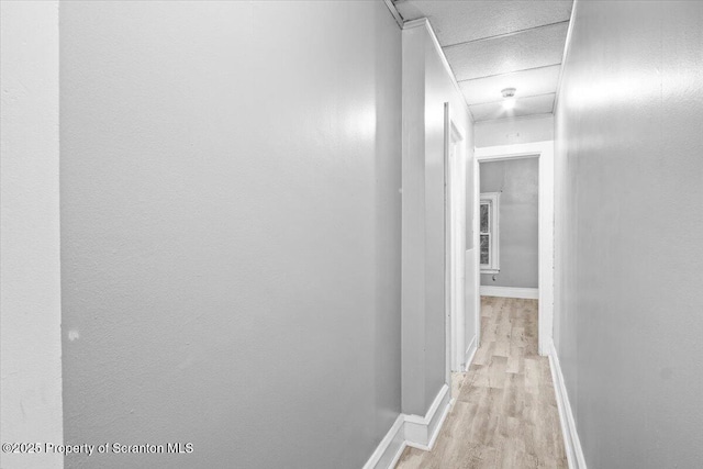 corridor featuring light wood finished floors and baseboards