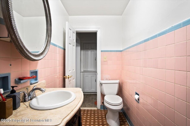 half bathroom featuring toilet, tile walls, and vanity