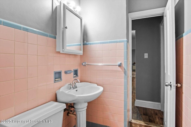 bathroom featuring toilet, wood finished floors, and tile walls